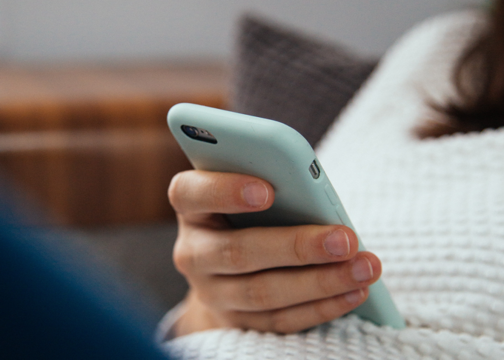 Fotografi föreställande kvinnohand hållandes i en mobiltelefon med mintgrönt skal
